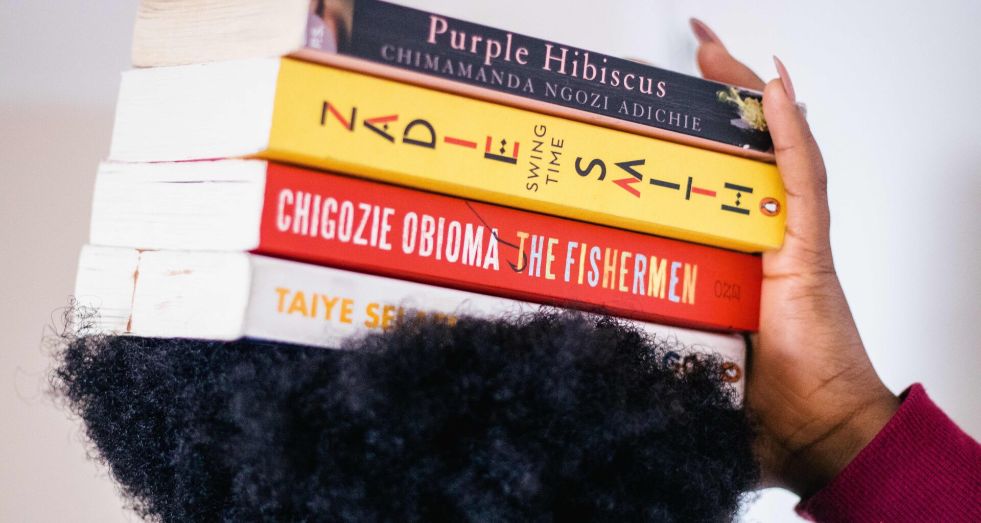 A Black woman balances works of Black literature on her head.