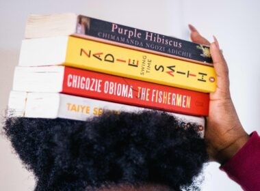 A Black woman balances works of Black literature on her head.